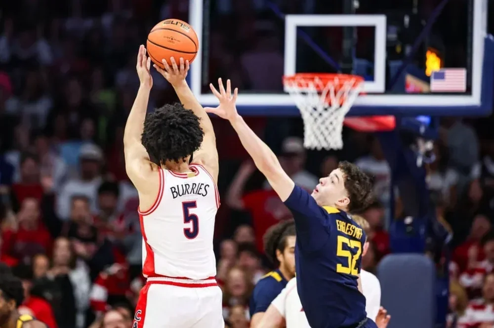 Jan 24, 2026; Tucson, Arizona, USA; Arizona Wildcats guard Brayden Burries (5) makes a three-point basket over West Virginia Mountaineers guard Treysen Eaglestaff (52) during the first half of the game at McKale Memorial Center. Mandatory Credit: Aryanna Frank-Imagn Images